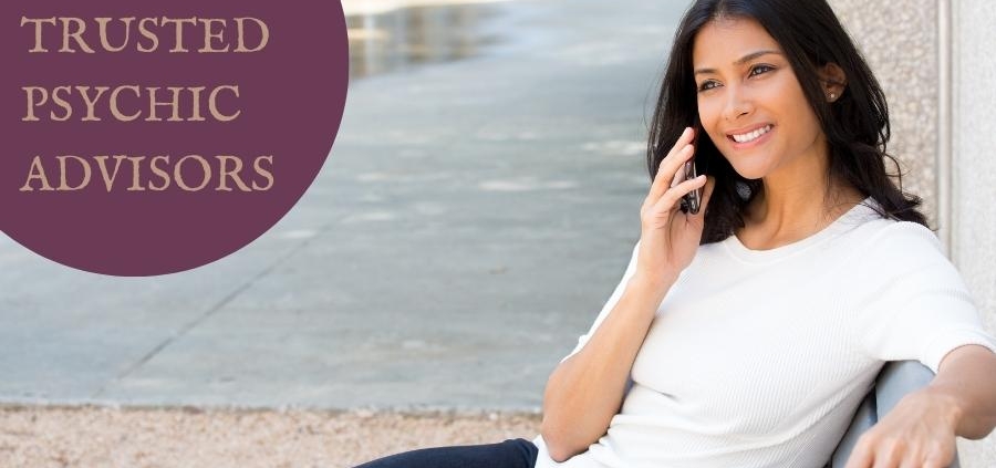 A woman sat on the bench on a phone. Text on the top left of the image says 'call our trusted psychic advisors'.